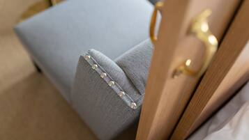 Primer plano de un sillón tapizado en azul claro con estampado de espiga y botones de perla.