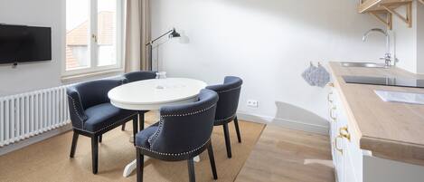 Una cocina moderna con una mesa redonda, dos sillas, estufa integrada y una ventana con cortinas.