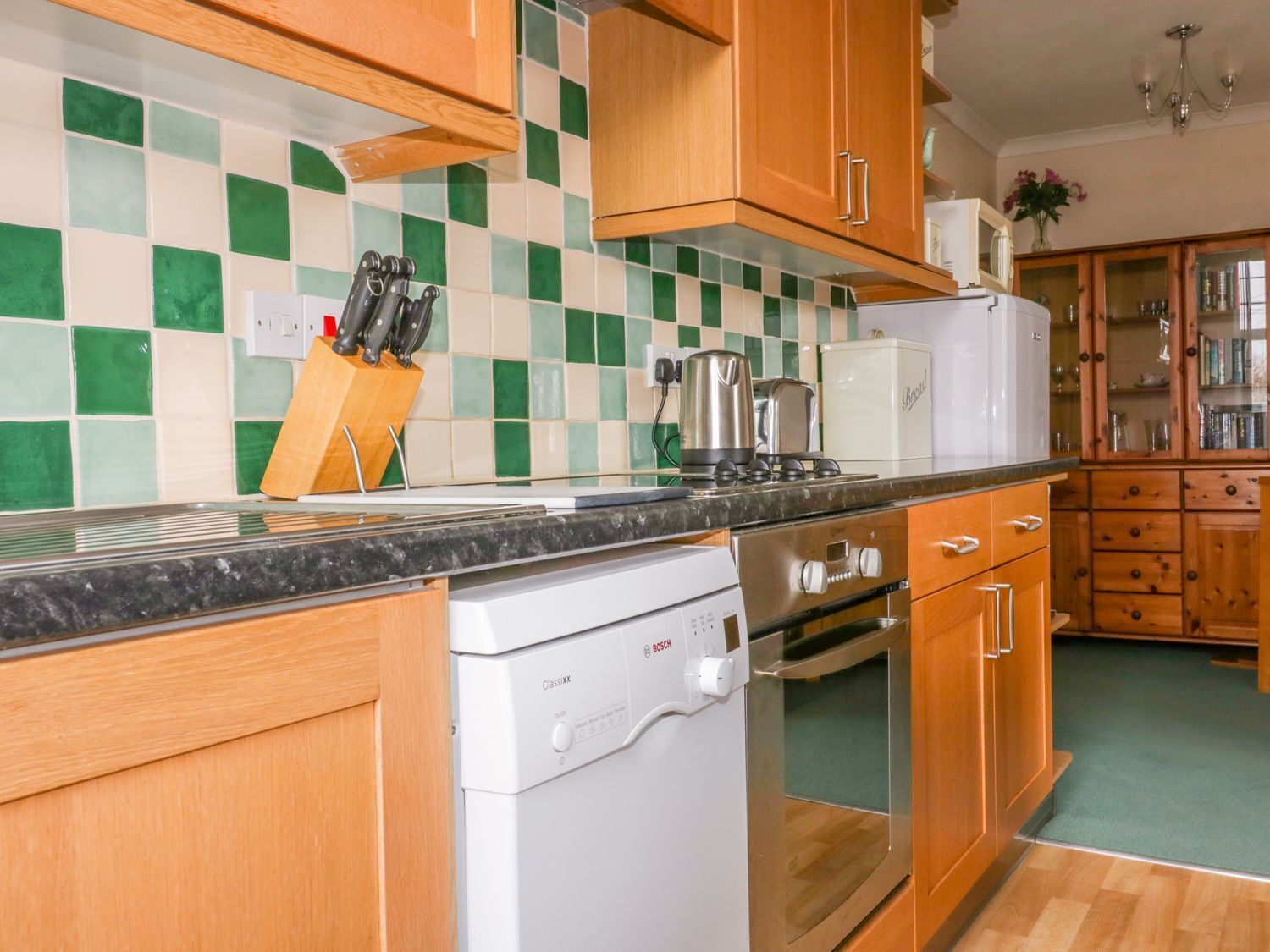 A kitchen with wooden cabinets, a Bosch dishwasher, a stainless steel range, and a checkered backsplash.