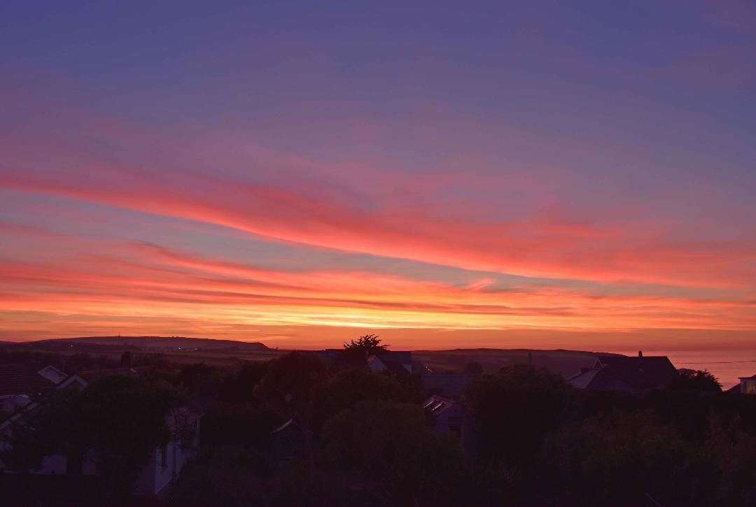 Un atardecer sobre un barrio residencial con casas y un cielo despejado.