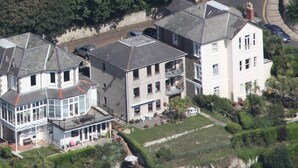 Una zona residenziale con diverse case, tra cui un grande edificio bianco con un balcone e un edificio più piccolo con un garage.