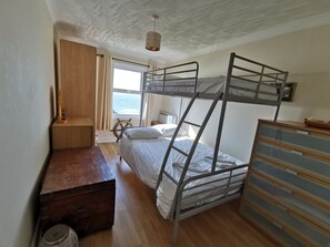 A bunk bed room with a wooden desk, a dresser, and a window with a view of the sea. - 2 bedroom apartment situated in spectacular location in Ventnor (Ventnor)