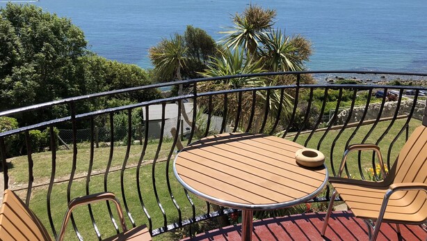 Un balcone con tavolo e sedie con vista sul mare.