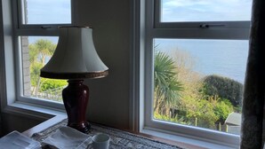 Una stanza con un tavolo, una lampada e vista sul mare attraverso ampie finestre.