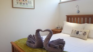 Une chambre à coucher avec un lit, une table de chevet, une lampe fixée au mur et un tableau encadré.