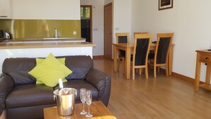 Un salon avec un canapé en cuir marron, une table basse en bois et un coin repas comprenant des chaises et une table en bois.
