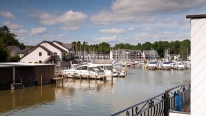 Un port de plaisance avec des bateaux amarrés, des bâtiments en arrière-plan et un ciel dégagé.