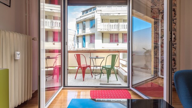 A room with a sliding glass door leading to an outdoor balcony with chairs and a table. - Pop-artment for two in city center (Athina)