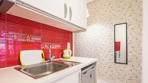 A modern kitchen with red tiles, a stainless steel sink, a white countertop, and a built-in dishwasher. - Pop-artment for two in city center (Athina)