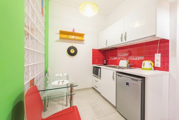 A compact kitchen with a glass dining table, a coffee machine, and a dishwasher.