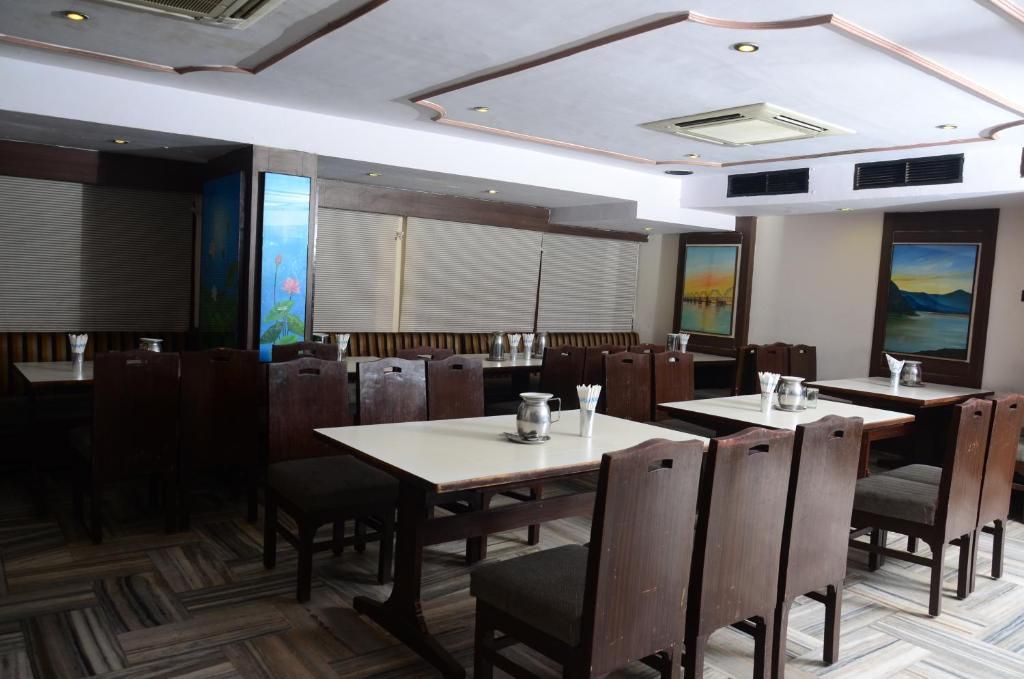 A restaurant with wooden tables and chairs, recessed ceiling lights, and artwork on the walls.