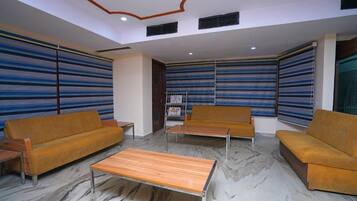 Um hall com paredes listradas, um sofá, uma mesa de centro e uma estante de livros.