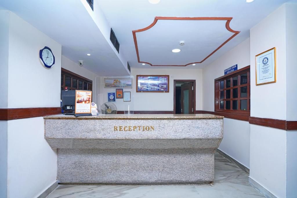A reception area with a marble counter labeled 'RECEPTION,' a clock, and framed certificates on the walls.