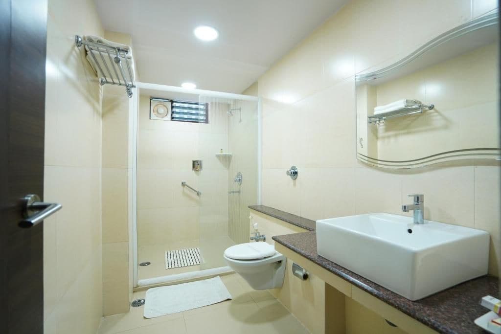 A modern bathroom with a glass-enclosed shower, a white sink, and a mirror above the sink.