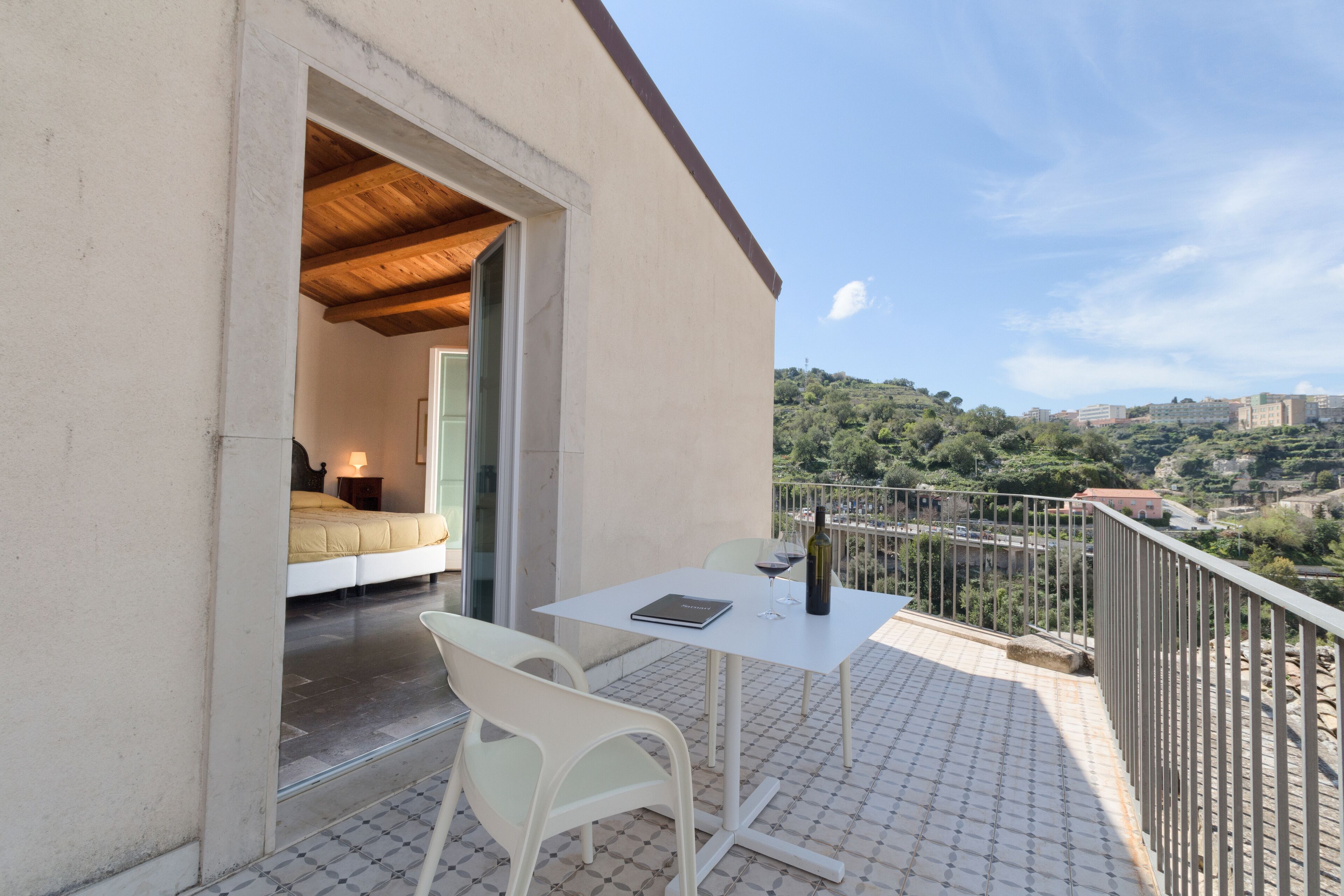 Ein Balkon mit Tisch, Stühlen und einer Weinflasche.