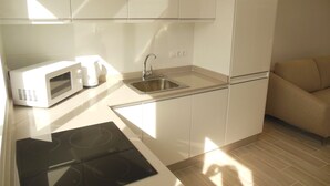 Une cuisine moderne avec des armoires blanches, un évier en acier inoxydable, un four à micro-ondes et une plaque de cuisson intégrée.