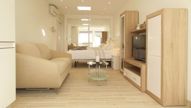 Une chambre d’hôtel moderne équipée d’un canapé, d’un lit, d’une télévision et d’une armoire en bois.