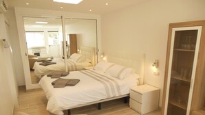 Une chambre à coucher moderne avec un lit, des tables de chevet, une table basse en verre et une armoire.