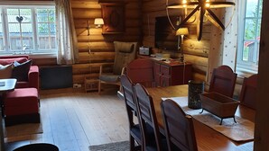A cozy log cabin interior with a dining area, a sofa, a television, and a rustic decor.