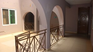 A hallway with a metal railing, a fire exit sign, and a door labeled "ROOM 07".