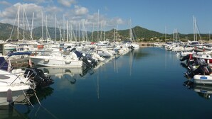 Un puerto deportivo con numerosas embarcaciones amarradas, agua tranquila y montañas al fondo.