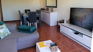 Un salon comprenant un canapé, un téléviseur, un coin repas et une grande carte accrochée au mur.