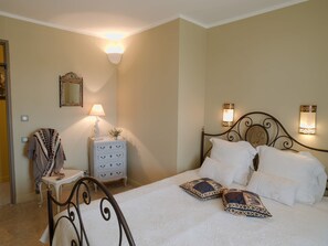A bedroom with a bed, two wall-mounted lamps, a dresser, a mirror, and a chair.