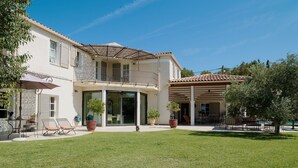 Una casa a due piani con patio coperto, prato e mobili da giardino.