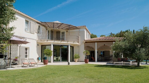 A two-story house with a covered patio, a lawn, and outdoor furniture.