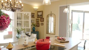 Una cucina con isola centrale, un lampadario e un'area pranzo con sedie e tavolo.