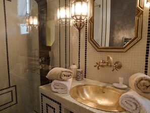 A bathroom with a gold sink, a mirror, and a towel rack.