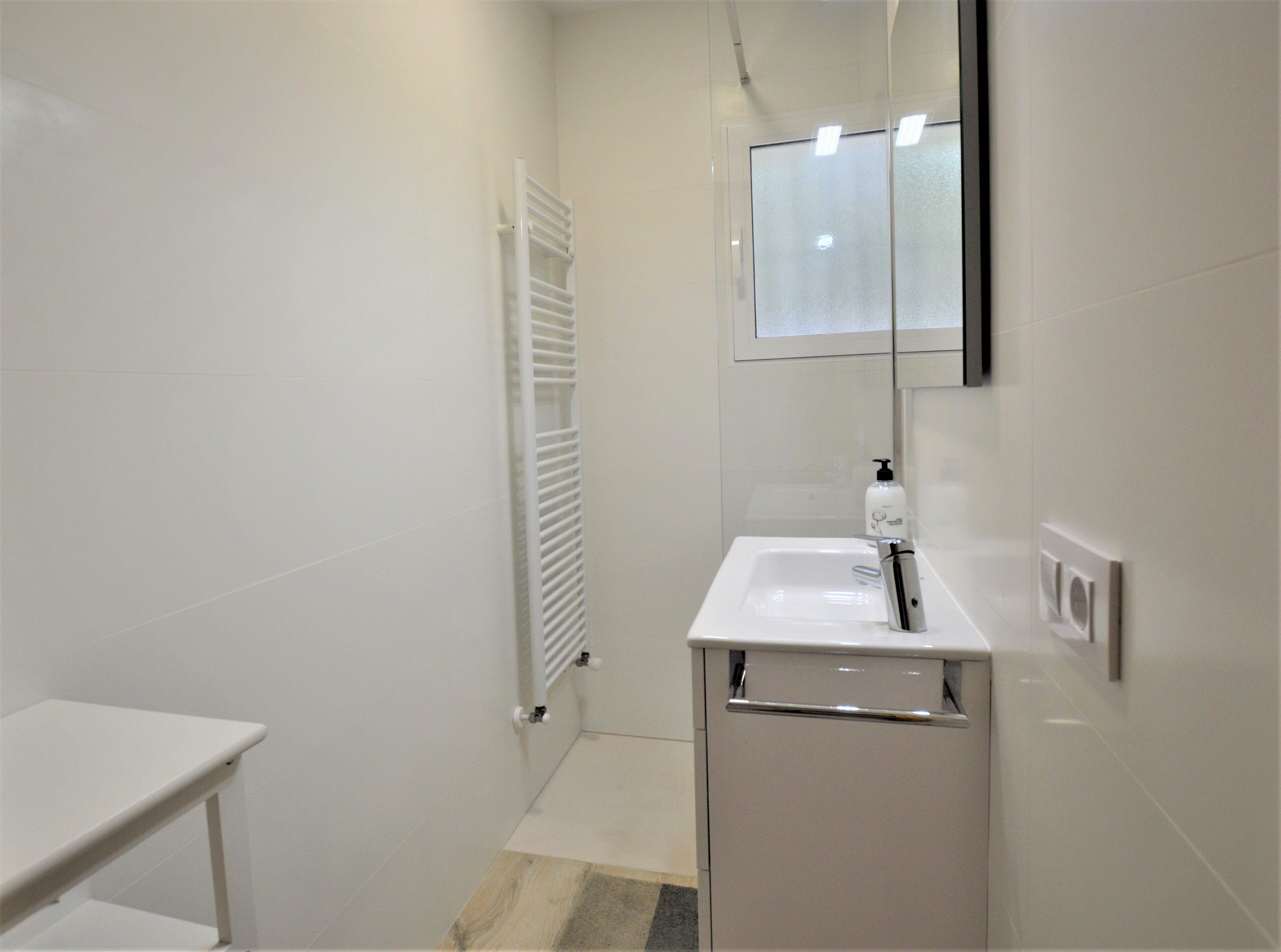 Une salle de bain moderne avec un lavabo blanc, un miroir et un porte-serviettes.