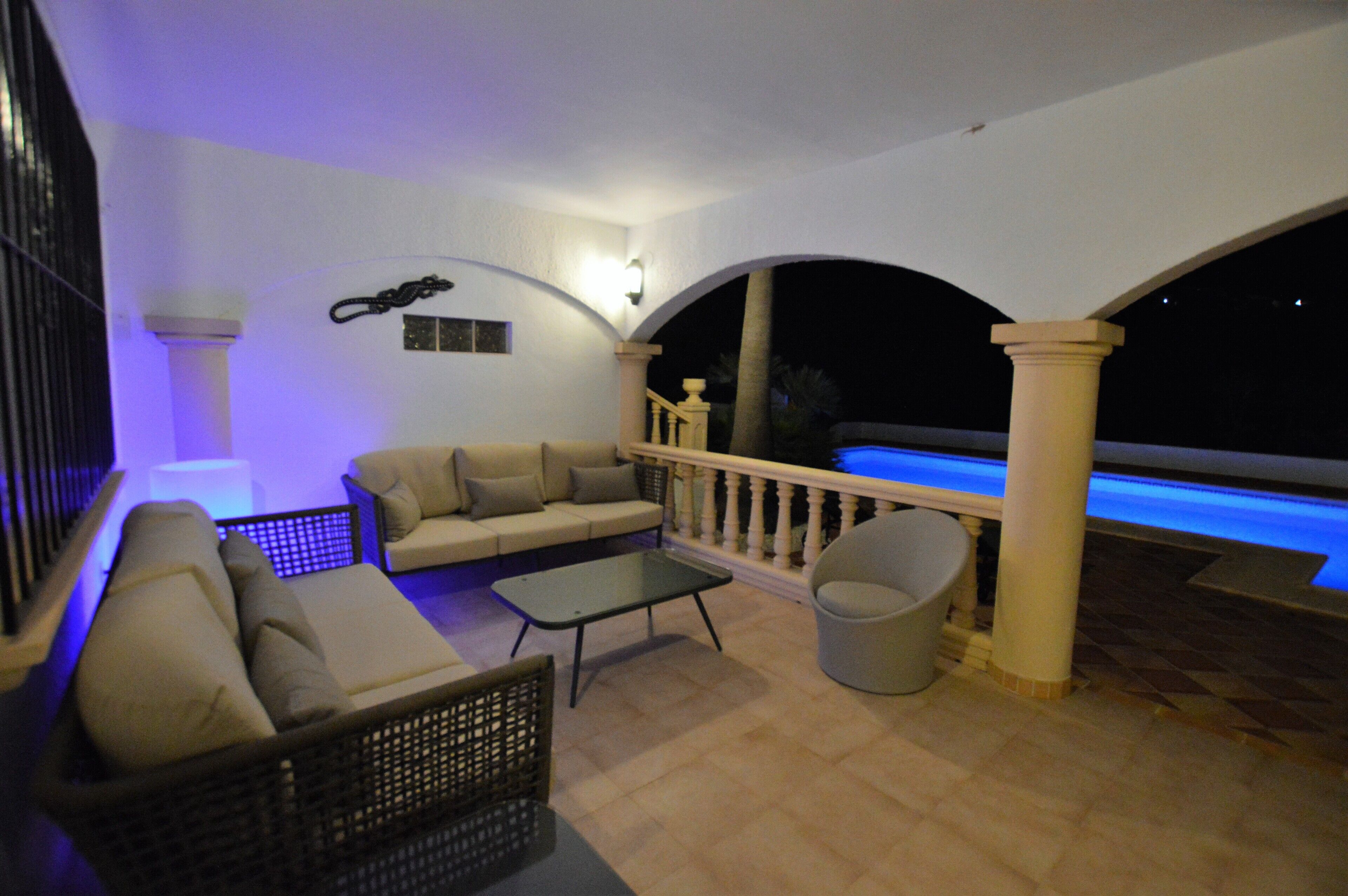 An outdoor patio area with a sofa, a small table, and a chair.