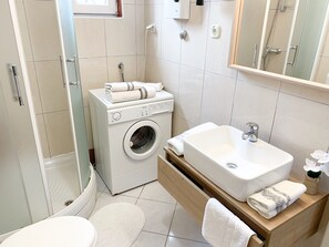 Un bagno moderno dotato di lavatrice, lavabo e WC.