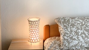 A bed with patterned bedding, a bedside lamp, and a framed picture on the wall.