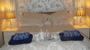 A neatly made bed with a tray of breakfast items, two pillows, and two bedside lamps. - Romantic Retreat (Penryn)