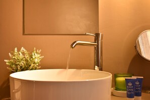 Un lavabo de salle de bain avec un robinet, un miroir et deux articles de toilette.