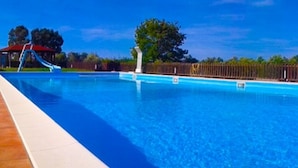Une piscine à l’eau d’un bleu cristallin, avec une terrasse en bois et un escalier en métal.
