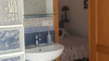A bathroom with a white sink, blue and white checkered floor, and a mirror with mosaic tiles.