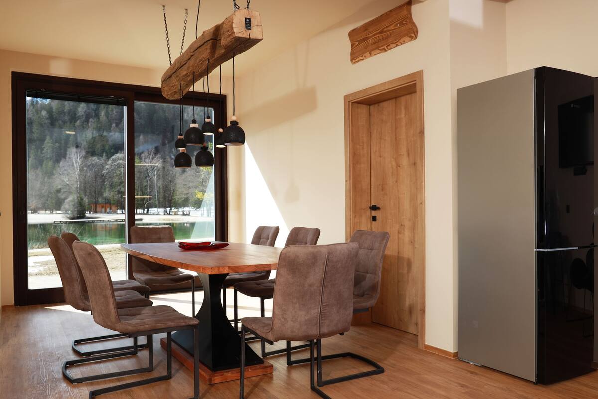A modern dining area with a wooden table, six chairs, and pendant lights.