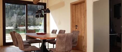 A modern dining area with a wooden table, six chairs, and pendant lights.
