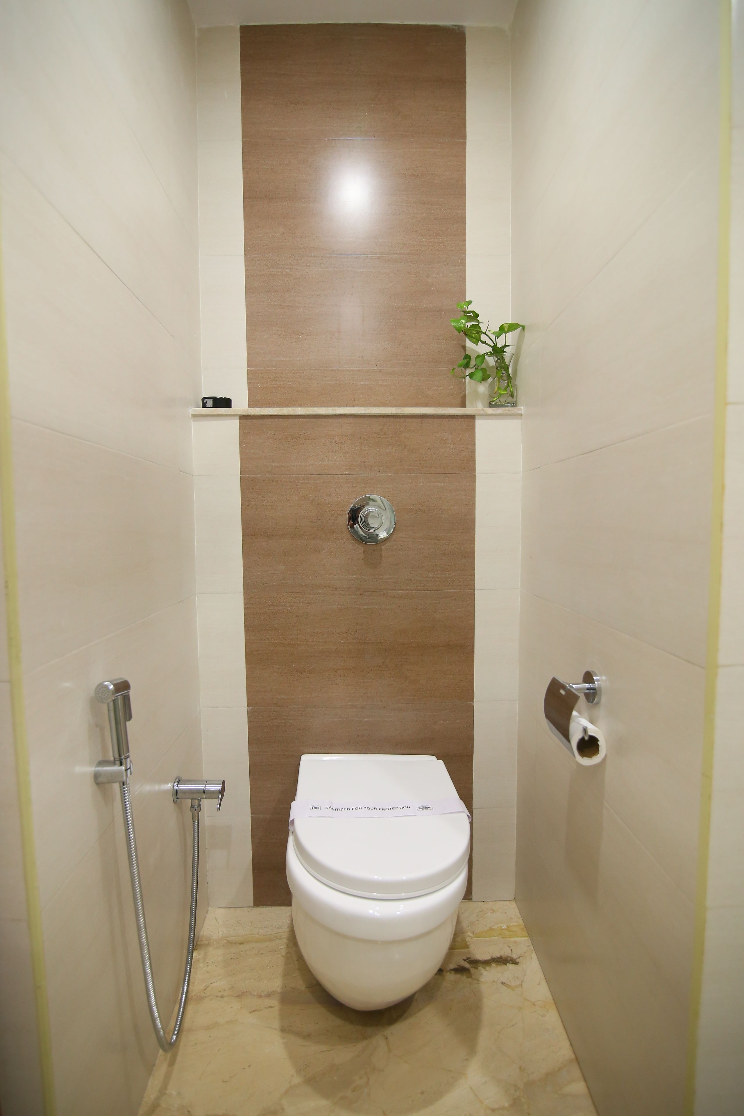 A small, modern bathroom with a white toilet, a shower, and a wooden accent wall.