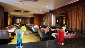 A restaurant with tables set for dining, a bar area with drinks, and a warm interior with curtains and a brick wall. - Daspalla Executive Court (Visakhapatnam)