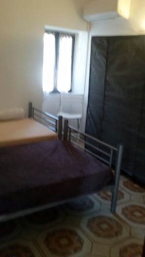 Een kamer met een bed, een stoel en een raam met gordijnen.