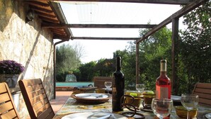 An outdoor dining area with a table set for two, featuring wicker plates, cutlery, and wine glasses. - Casale Eredità cottage countryside Tiber Valley  private  pool 70 km North Rome (Orte)
