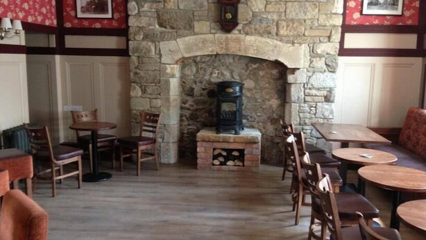 A cozy interior with a stone fireplace, wooden furniture, and a red floral wallpaper. - Castle Inn (Strabane)