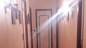 Un couloir doté d’un sol carrelé, une porte au fond et des luminaires fixés au mur.