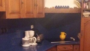 Une cuisine avec des meubles en bois, un plan de travail bleu et un sol carrelé.