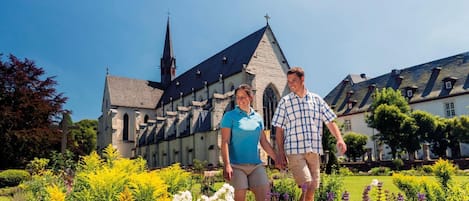A historic church with a tall spire, surrounded by a well-maintained garden with various flowers and shrubs.