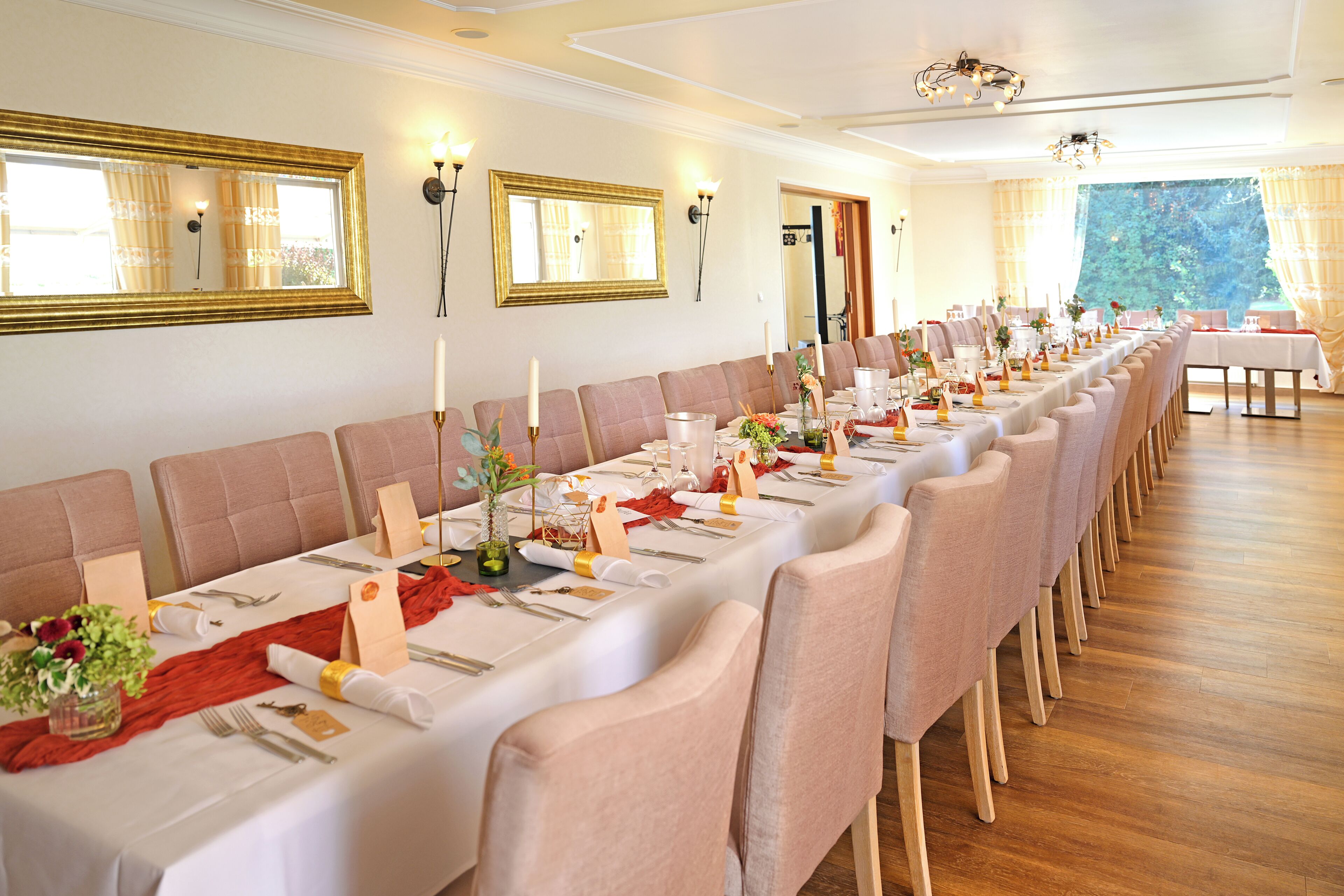 A long dining table set for a formal event with multiple chairs, candles, and floral centerpieces.